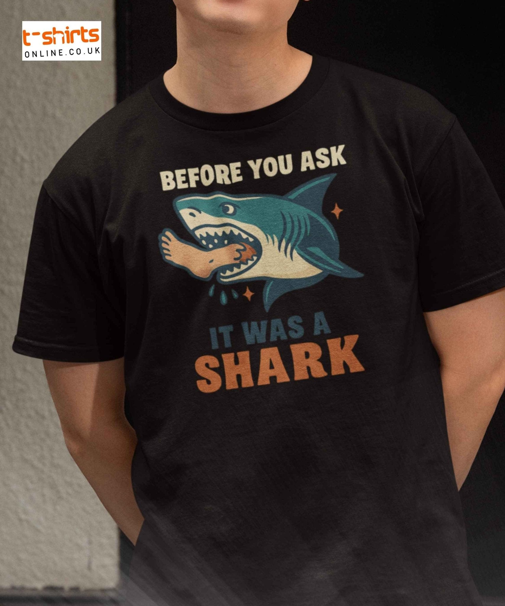 A vintage-style shark with a human foot in its mouth and bold text saying, “Before You Ask, It Was A Shark.”
