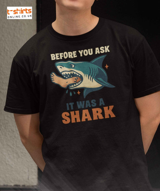 A vintage-style shark with a human foot in its mouth and bold text saying, “Before You Ask, It Was A Shark.”