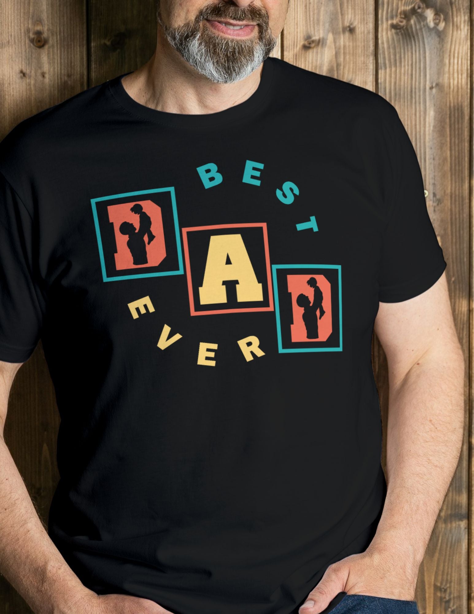 Man wearing a black T-shirt with colorful retro block letters spelling “Best Dad Ever” and silhouettes of a father and child.