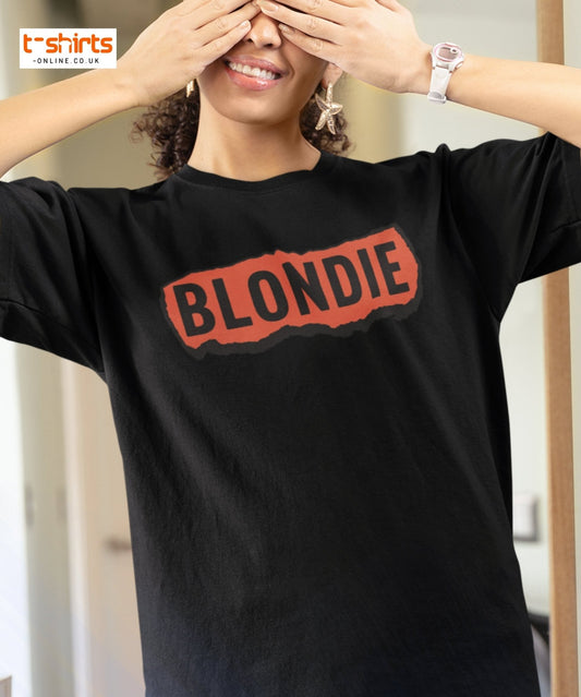 Person wearing a black t-shirt with 'BLONDIE' printed on it, with a blurred background.