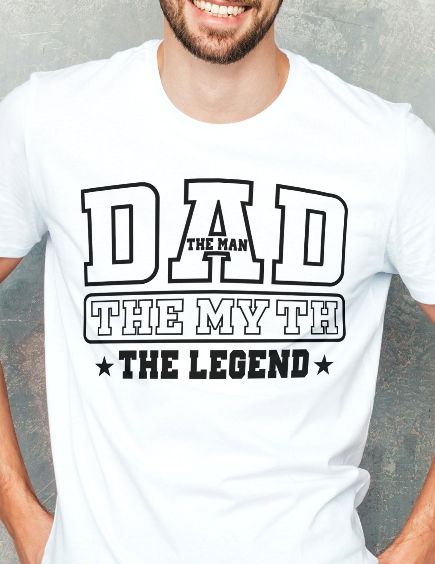 Man wearing a white T-shirt that reads “Dad – The Man, The Myth, The Legend” in bold varsity-style black text.
