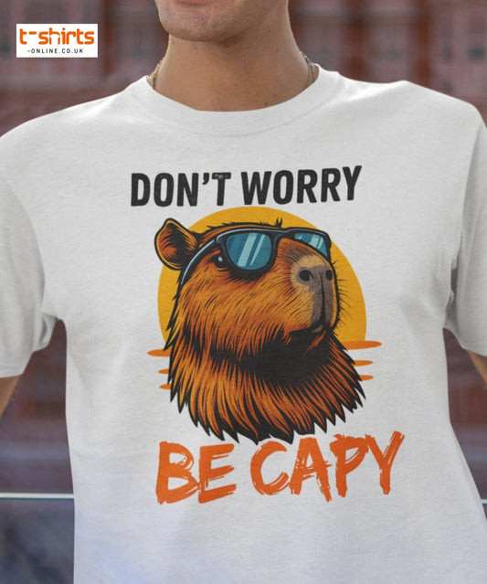 White t-shirt with bear graphic and text 'Don't worry be capy' on a blurred background