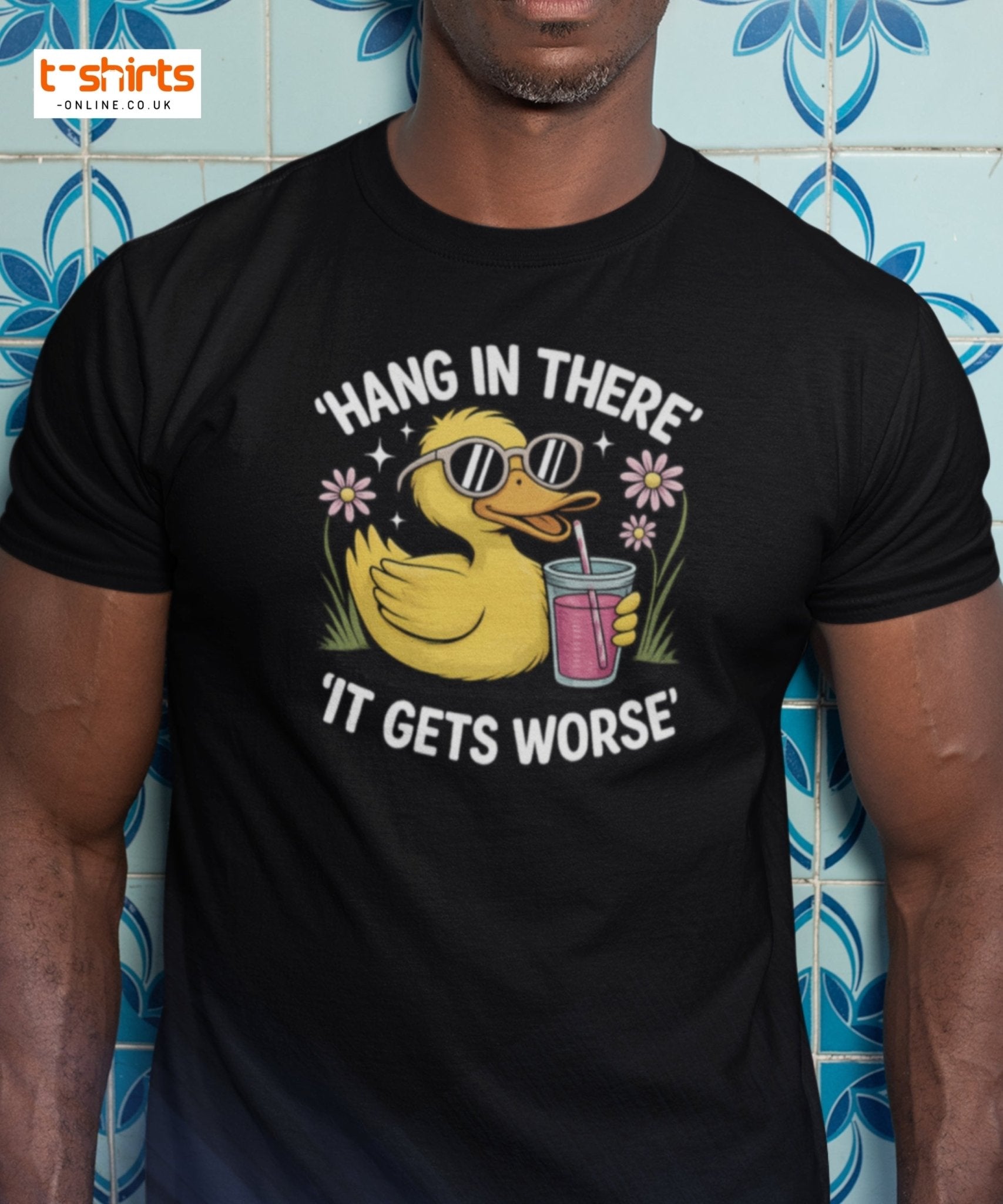 Person wearing a black t-shirt with a rubber duck graphic and text against a blue tiled wall.