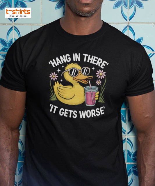 Person wearing a black t-shirt with a rubber duck graphic and text against a blue tiled wall.