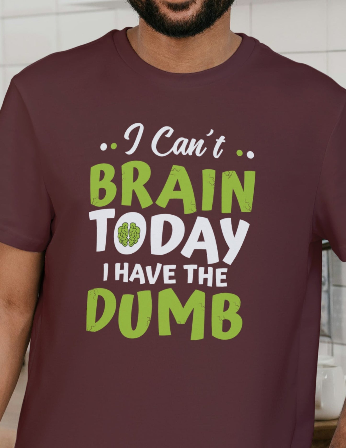 Man wearing a maroon t-shirt with the funny quote “I Can’t Brain Today, I Have the Dumb” in bold green and white letters.