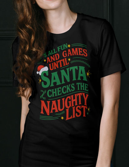 Woman wearing a black Christmas t-shirt with the phrase “It’s All Fun and Games Until Santa Checks the Naughty List”