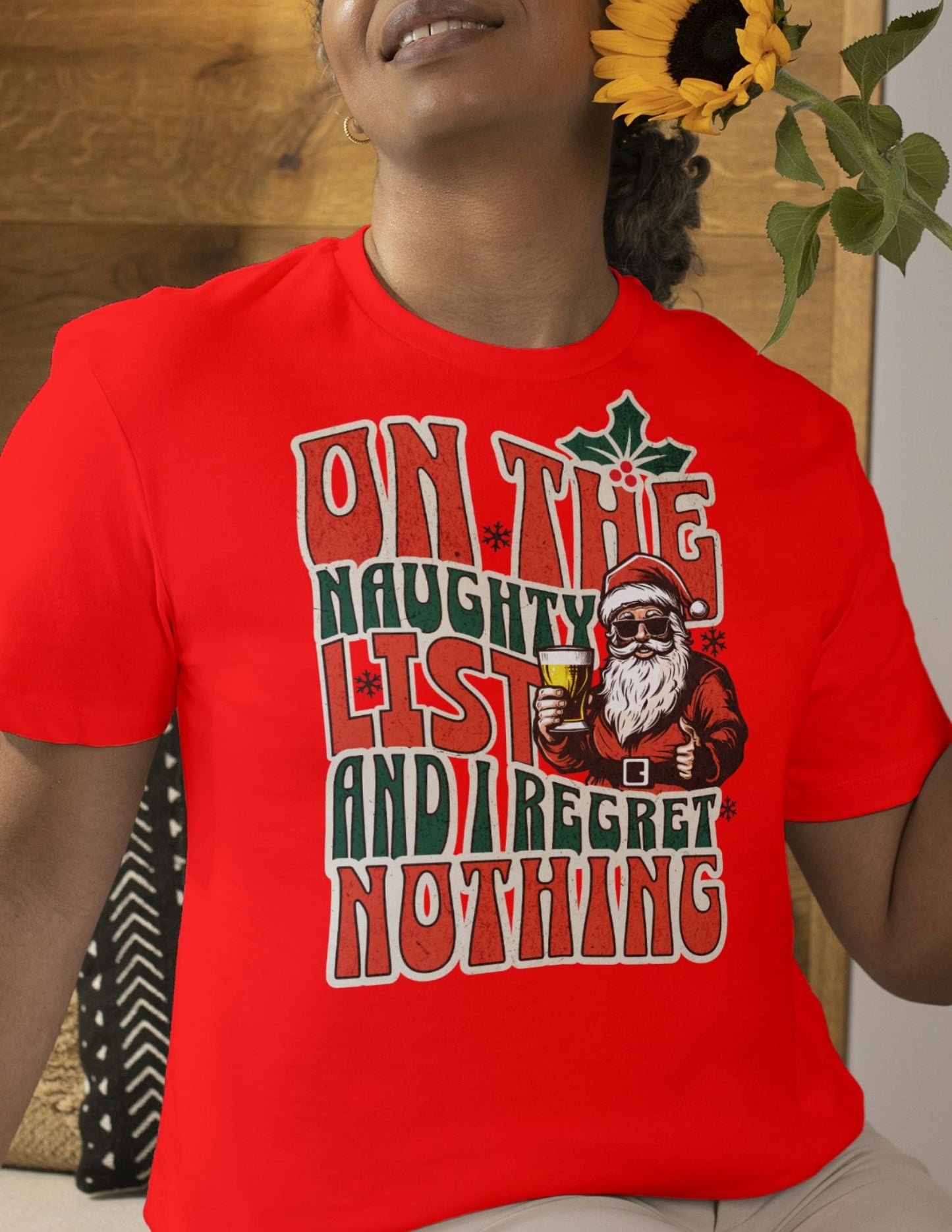 Red t-shirt with bold retro-style text that reads “On the Naughty List and I Regret Nothing” alongside a festive Santa