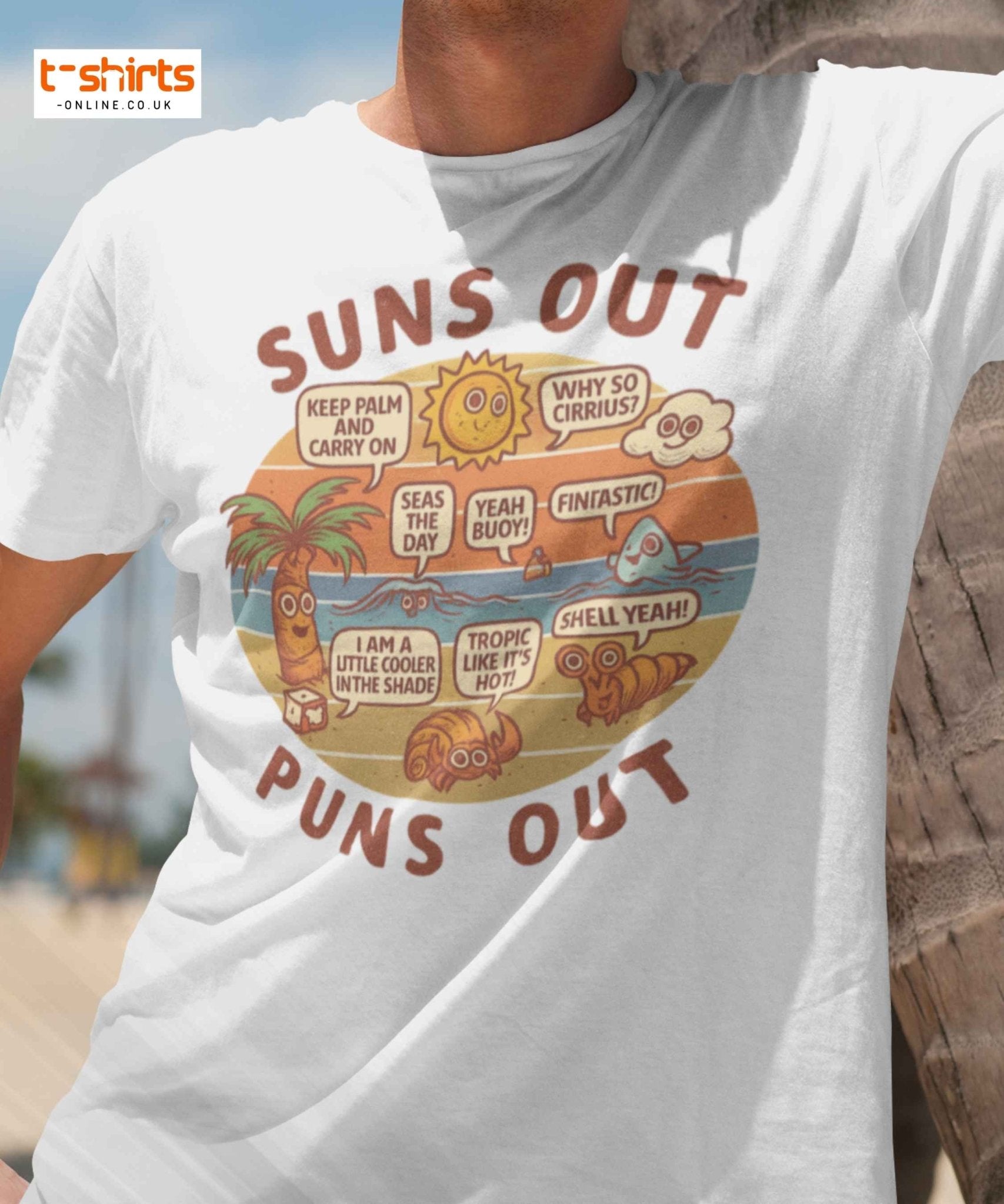 White t-shirt with a colorful graphic and text 'Suns Out Puns Out' worn by a person at a beach.