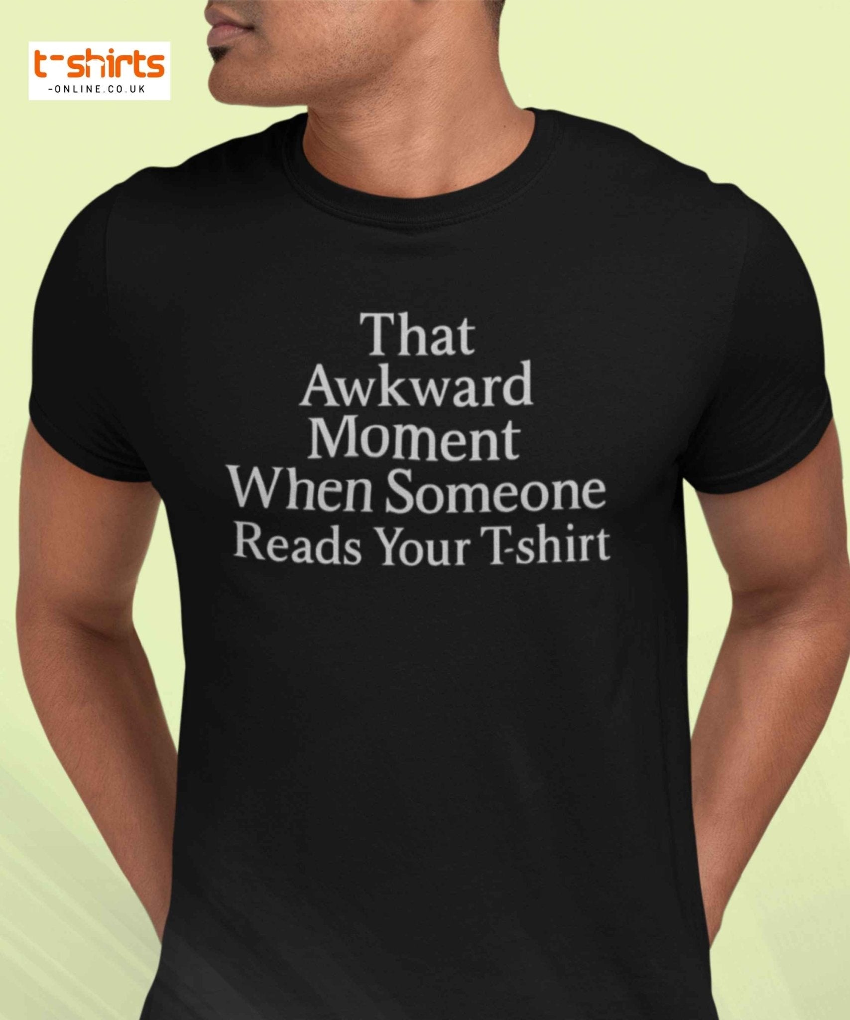 Black t-shirt with humorous text worn by a person on a light yellow background